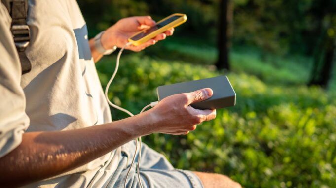 0_Man-charging-smartphone-with-power-bank-in-park-during-outdoor-walk-in-nature-Smartphone-dependence-in-daily-life.jpg